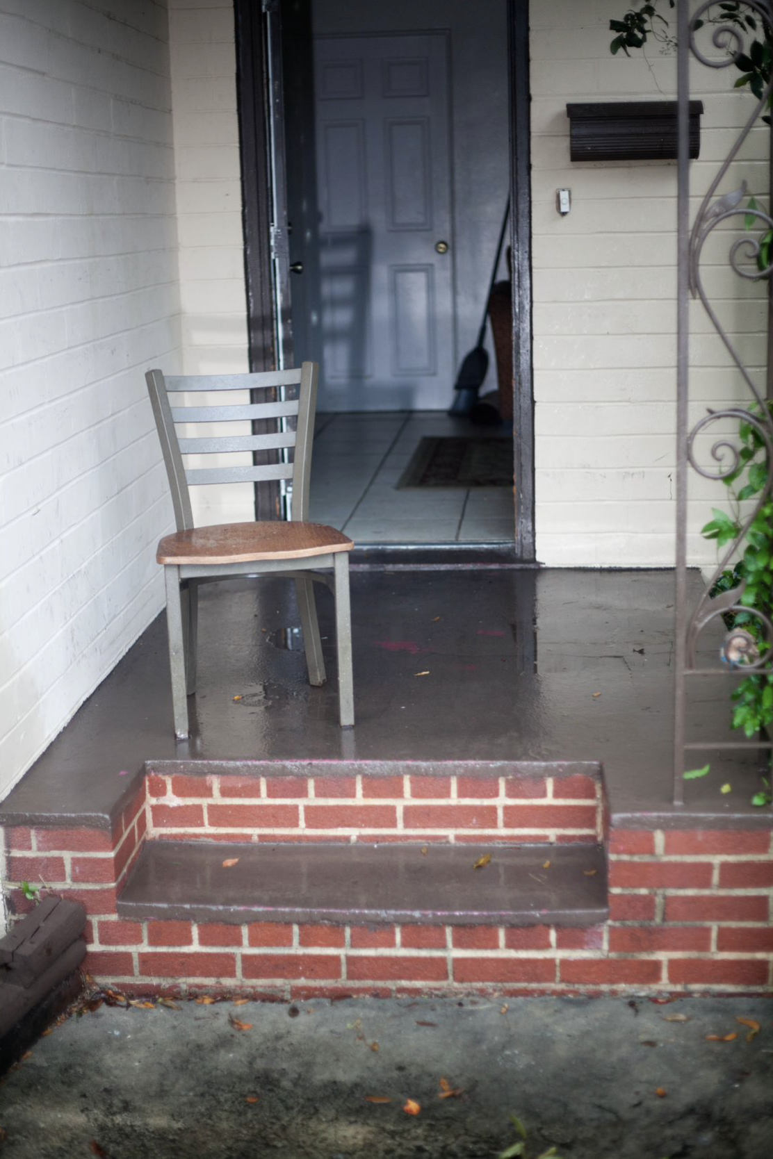A chair stands on top of two brick stairs- the front door of Bobbie's home is open to see inside. 
